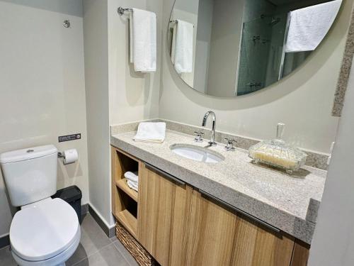 a bathroom with a toilet and a sink with a mirror at Noon Vila Madalena in Sao Paulo