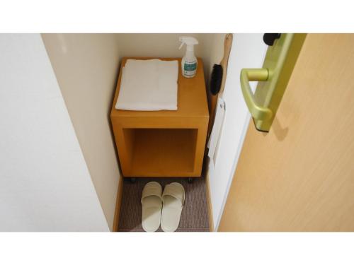 a small table with two shoes next to a door at Smile Hotel Shizuoka Yoshida Inter - Vacation STAY 90880v 