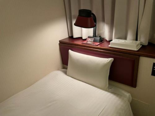 a hotel room with a bed and a lamp and a phone at Smile Hotel Sasebo - Vacation STAY 92159v in Sasebo