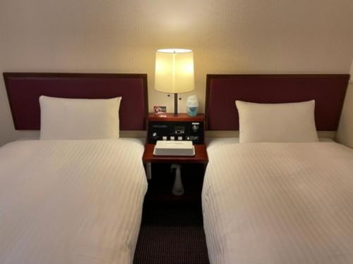 a hotel room with two beds and a table with a lamp at Smile Hotel Sasebo - Vacation STAY 92151v in Sasebo