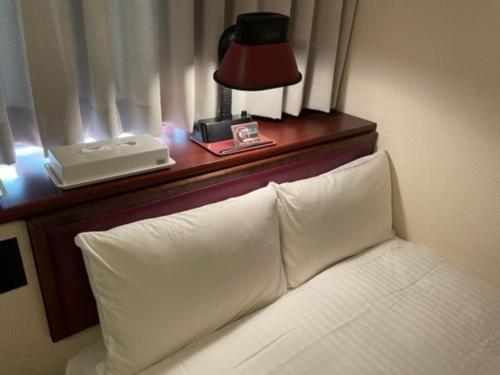a bed with a table with a lamp and a telephone at Smile Hotel Sasebo - Vacation STAY 92147v in Sasebo