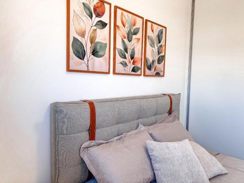 three paintings on a white wall above a couch at Apartamento 1 quarto in Brusque