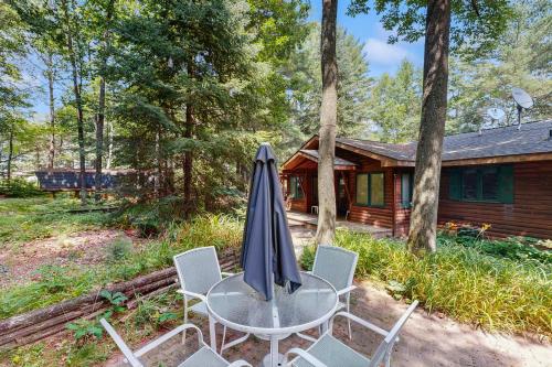 a table with an umbrella and chairs in front of a cabin at Good Time Inn in Lake Tomahawk