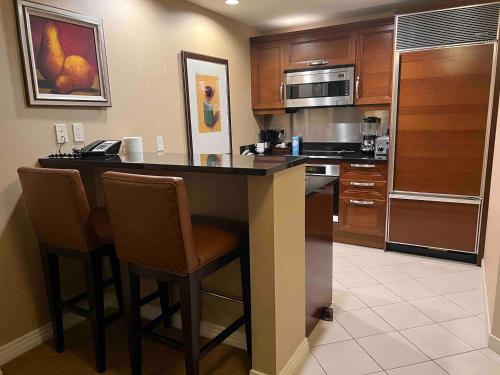 a kitchen with a bar with chairs and a microwave at Mgm 1 Bedroom Balcony And Or Studio Luxury Suites in Las Vegas
