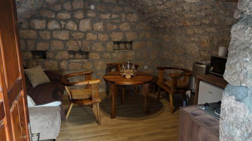 a small table and chairs in a room with a stone wall at Jablan Stone House - Kamena Kuća Jablan in Cetinje