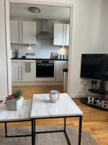 a living room with a table and a kitchen at 1 bed Flat Greater London in New Malden