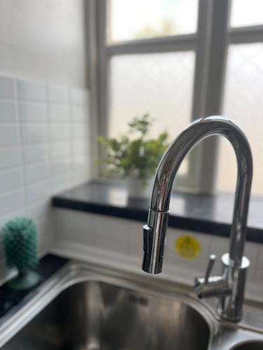 a kitchen sink with a faucet next to a window at 1 bed Flat Greater London in New Malden