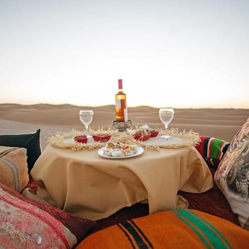 a table with a bottle of wine and wine glasses at Sahara Soul luxury Camp in Merzouga