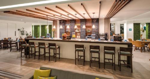a restaurant with a bar with stools at Tikal Futura Hotel & Convention Center in Guatemala