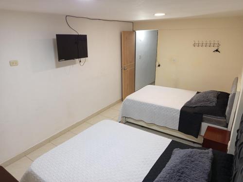 a room with two beds and a tv on the wall at habitación Salome in Dosquebradas