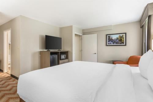 a bedroom with a white bed and a tv at Best Western Plus Sonora Oaks Hotel and Conference Center in Sonora
