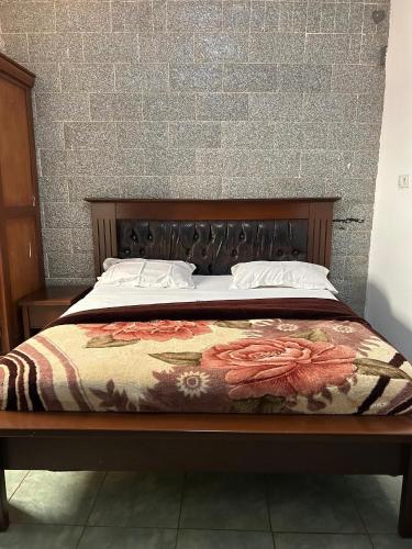 a bed with a wooden headboard with a flower blanket at Prodiges Hôtel in Yaoundé