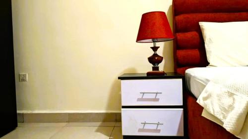 a bedroom with a bed with a red lamp on a night stand at Bati Valley Guest House in Kigali