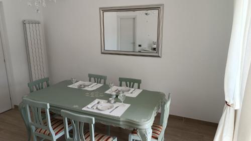 a green table with chairs and a mirror at LE GEMME Bed & Breakfast con parcheggio e giardino in Casarza Ligure
