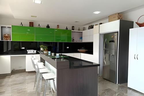 a kitchen with black and green cabinets and a refrigerator at Reserva tu casa rodeada de naturaleza en Anapoima in La Mesa