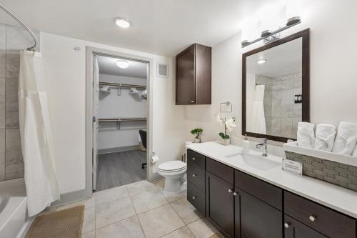 a bathroom with a sink and a toilet and a mirror at Chill & Tone 1BR Frisco King & Sofa, Gym & Pool in Frisco