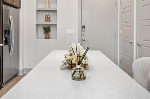 a white kitchen with a vase of flowers on a counter at Chill & Tone 1BR Frisco King & Sofa, Gym & Pool in Frisco
