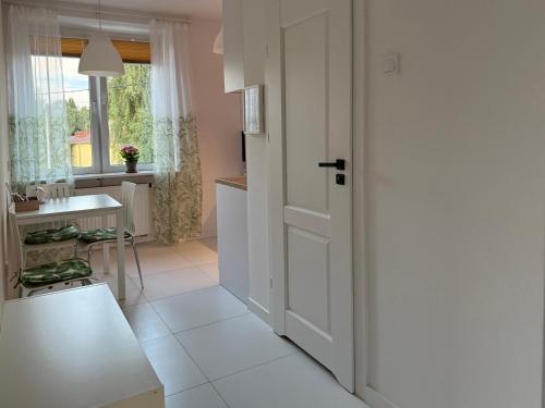 a kitchen with a white door and a table at Apartament Żabie Oczko in Zator