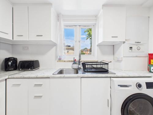 a white kitchen with a sink and a dishwasher at Stylish 4BR North London Home by D3 Short Stay, Sleeps 9, Piccadilly Line in London