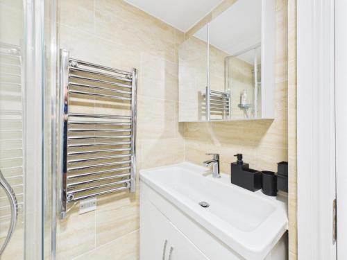 a bathroom with a sink and a mirror at Stylish 4BR North London Home by D3 Short Stay, Sleeps 9, Piccadilly Line in London
