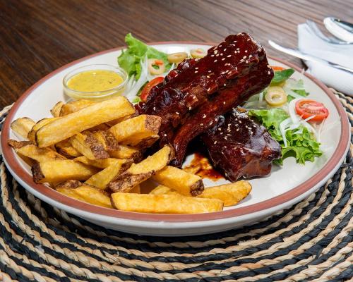 a plate of food with meat and french fries at Fernandina Hotel & Spa in Puerto Ayora