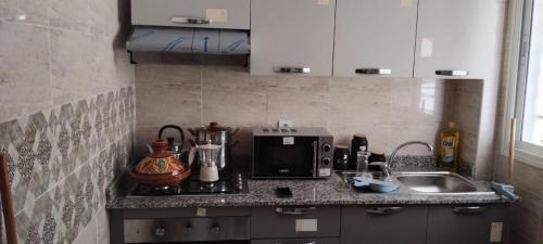 a kitchen counter with a microwave and a sink at Sunset Home in Tangier