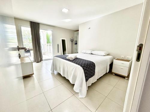 ein weißes Schlafzimmer mit einem Bett und einem Fenster in der Unterkunft Golf Ville Residence Resort, apartamento 3 suítes, 110m2, Porto das Dunas próx ao Beach Park in Aquiraz