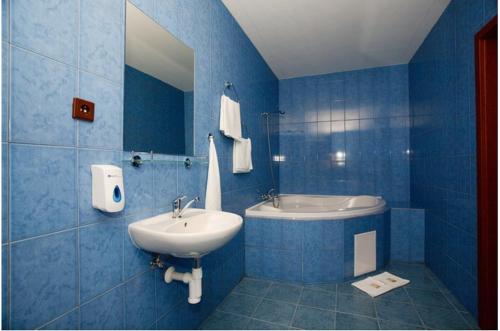 Hotel U Jelena في هافروف: حمام أزرق مع حوض استحمام ومغسلة