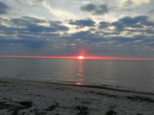 a sunset on the beach with the sun in the water at 5 person holiday home in Tisvildeleje in Tisvildeleje