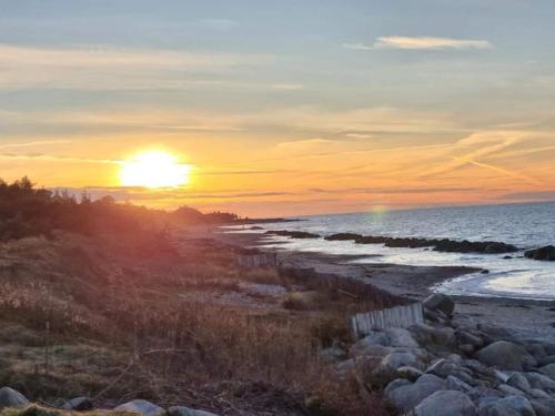 a sunset on a beach with the sun setting at 6 person holiday home in Gilleleje-By Traum in Gilleleje