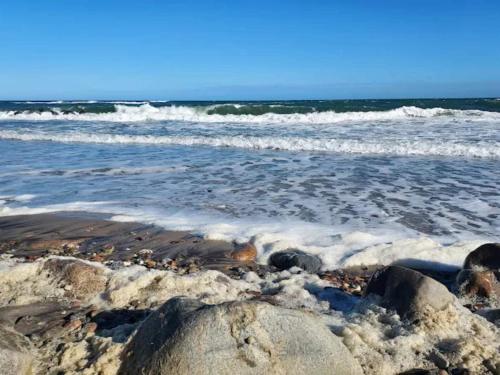 a beach with rocks and the ocean with waves at 6 person holiday home in Gilleleje-By Traum in Gilleleje