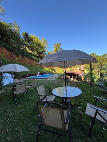 a group of tables and chairs with an umbrella at Chalé Ecos do Jucu sauna-ofurô-piscina aquecida-wifi in Domingos Martins