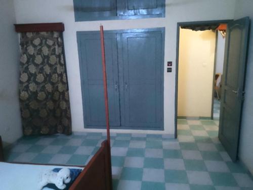 a bedroom with a blue door and a checkered floor at Chic Appartement 2chambres in Godomey