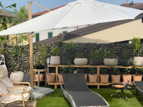 a patio with chairs and an umbrella and plants at Casa Bianca Luino Terrace View in Luino