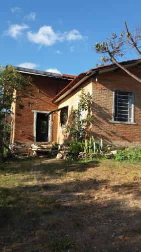 an old brick house with a window and a yard at Winará - Turismo de aventura in São Thomé das Letras