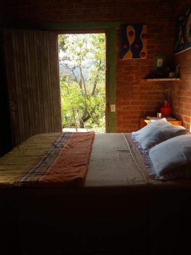 a large bed in a room with a window at Winará - Turismo de aventura in São Thomé das Letras
