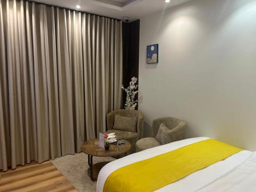 a bedroom with a bed and two chairs and a table at Hala 9B استوديو فندقي فاخر في قلب الملقا in Quai