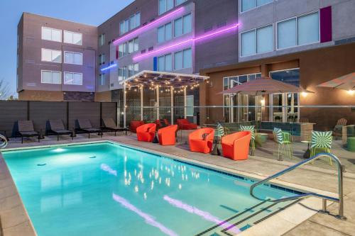a swimming pool with orange chairs and a building at Aloft Sacramento Airport Natomas in Sacramento