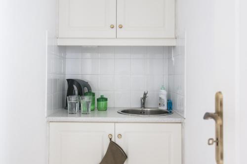 a kitchen counter with a sink and white cabinets at Concierge Downtown in Athens