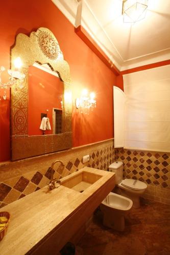 a bathroom with a sink and a toilet and a mirror at Hotel Rural Posada del Moro in Cazalla de la Sierra