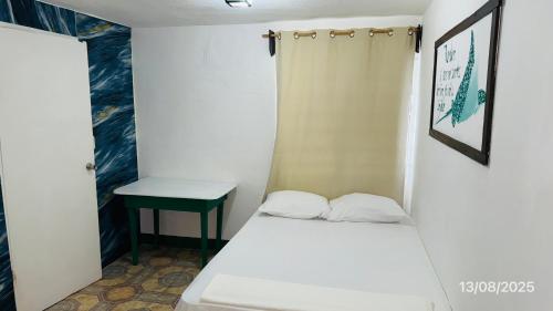 a small bedroom with a bed and a table at The Wave Hostel Corn Island in Corn Island
