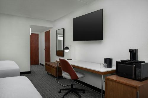 a hotel room with a desk with a television and a bed at Courtyard by Marriott Bloomington in Bloomington
