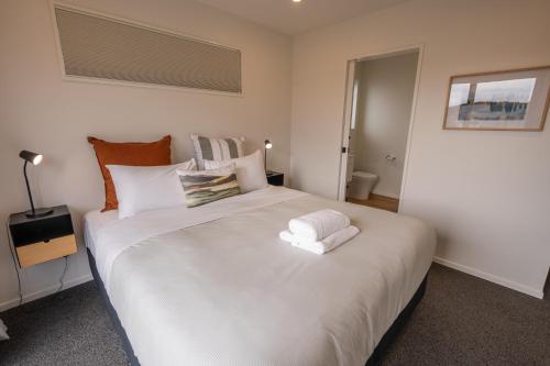 a bedroom with a large white bed with two towels on it at Tussock Horizons in Twizel