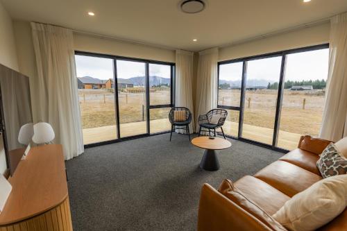a living room with a couch and chairs and windows at Tussock Horizons in Twizel