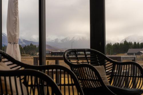 three benches sitting in front of a window with mountains at Tussock Horizons in Twizel