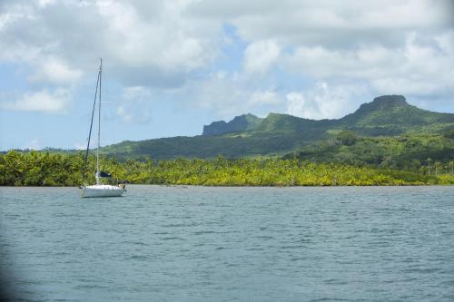 a sail boat in the water with mountains in the background at RAIATEA - Fare Coco in Taoru