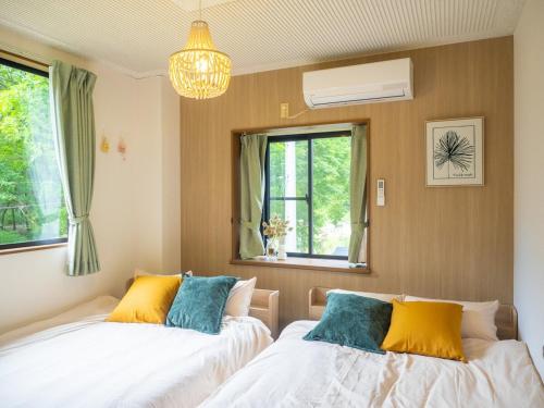 two beds in a room with two windows at Harmonia 那須,大人数,カラオケ,屋根付きBBQ,敷地内の小川 in Nasu