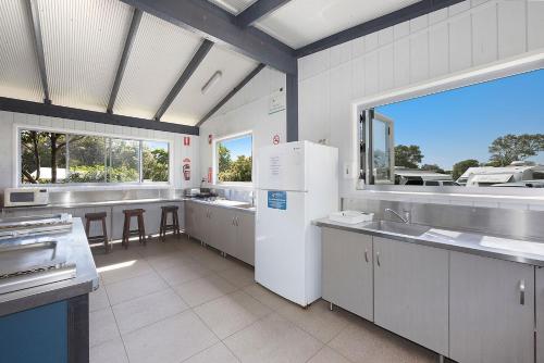 a large kitchen with sinks and a white refrigerator at Reflections Lennox Head - Holiday Park in Lennox Head