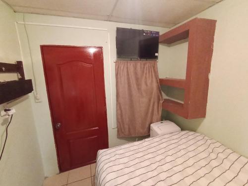a small bedroom with a bed and a red door at Casa de huéspedes libertad in San Salvador