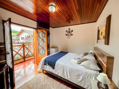 a bedroom with a bed and a balcony at Pousada Avenida in Monte Verde